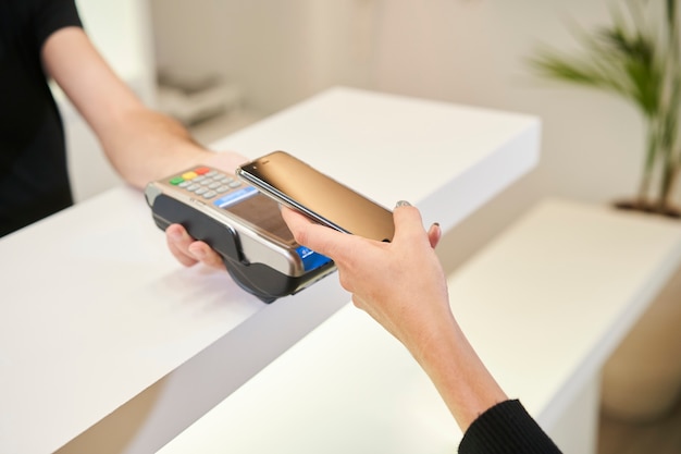 Close up shot of a customer's hands paying with a smartphone