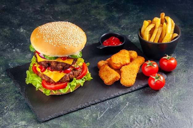 Close up shot of delicious sandwich and chicken nuggets ketchup on dark color tray tomatoes on black surface