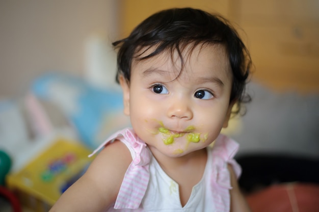 Close up shot a face Asian baby with mouth soiled food after eating, looking out