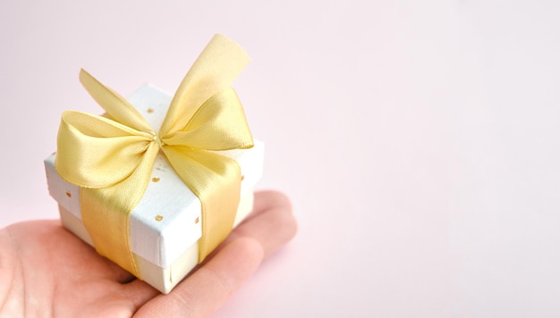 Close up shot of female hands holding a small gift wrapped with\
pink ribbon