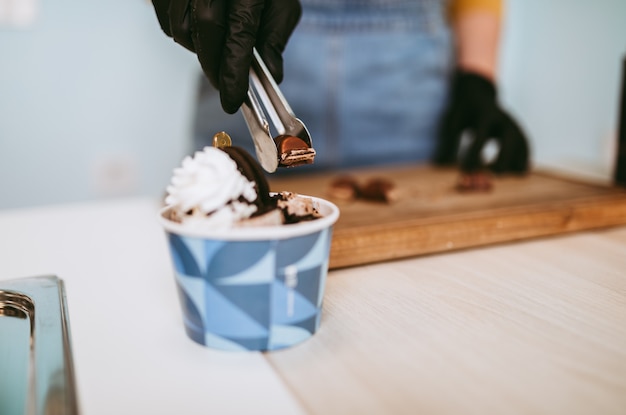 Immagine ravvicinata delle mani della lavoratrice che lavorano in gelateria artigianale.