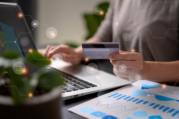 Close up shot of females hands holding credit card typing message on laptop for shopping online with technology icons