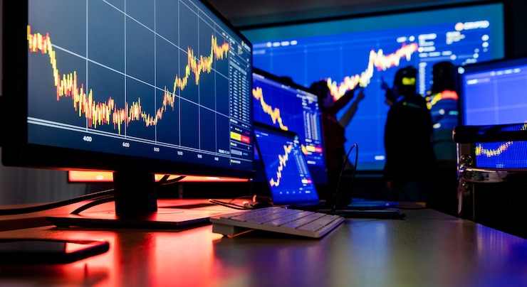 Photo close up shot of financial analysis graph chart stock exchange bitcoin cryptocurrency report on computer screen monitors and laptop on working in trading room while broker meeting in shadow behind.