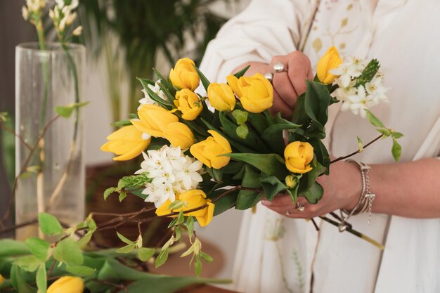 close up shot of florist making bouquet of yellow tulips in flower shop