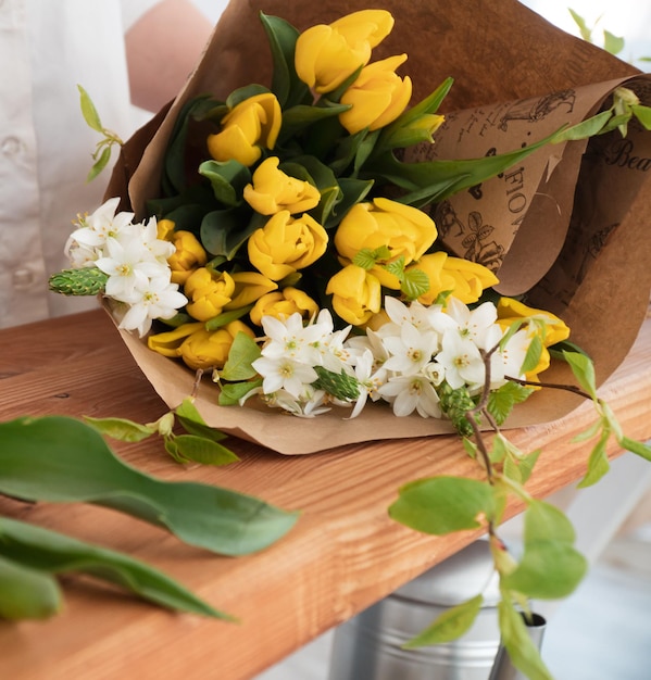 close up shot of florist making bouquet of yellow tulips in flower shop