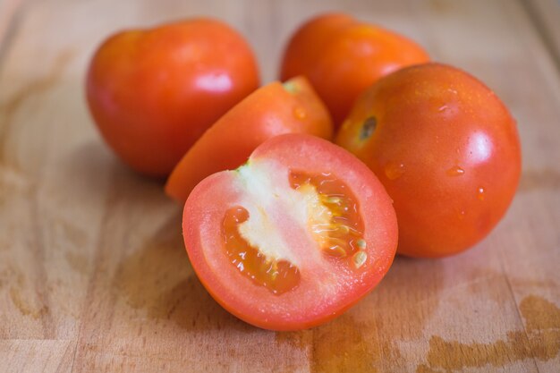 Chiuda sul colpo dei pomodori freschi sul tagliere di legno. fuoco selettivo.