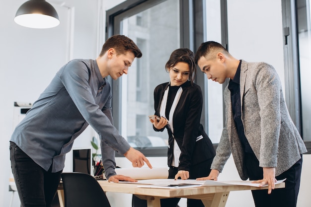 Close-up shot of group of architects drawing building plan together at office