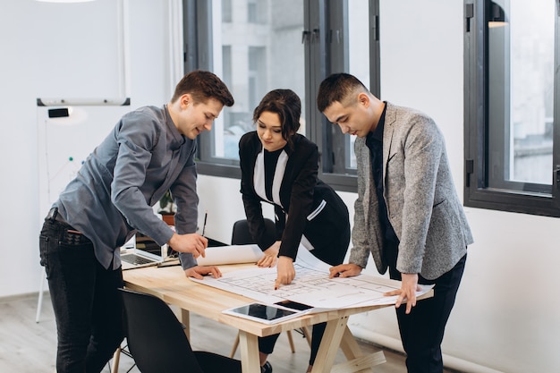 Close-up shot of group of architects drawing building plan together at office