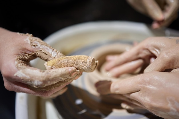 Close up shot of hands of crafts people working with clay in\
pottery studio