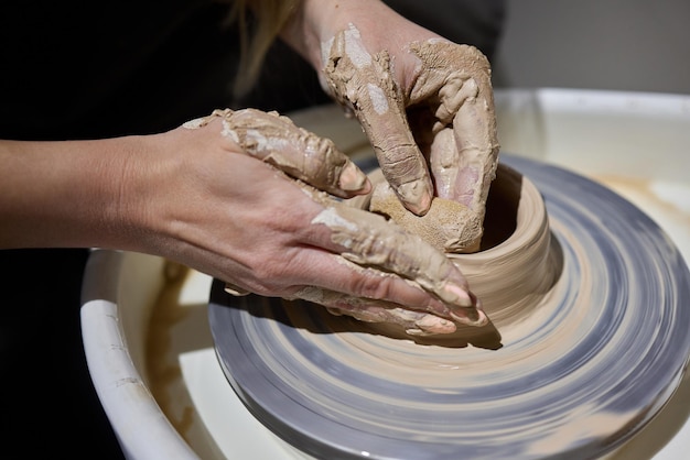 Close up shot of hands of crafts people working with clay in\
pottery studio