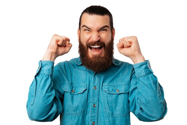 Photo close up shot of a handsome pleased bearded man is making the winner gesture