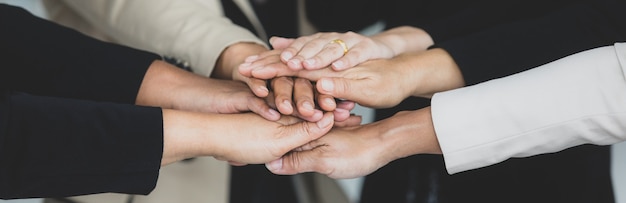 Close up shot of holding hands of unidentified unrecognizable successful female businesswoman group together in formal business suit wears empower encourage as trust teamwork partnership agreement.