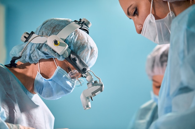 Фото Крупным планом в операционной, ассистент раздает инструменты хирургам во время операции. хирургия в прогрессе. профессиональные врачи, выполняющие операции.