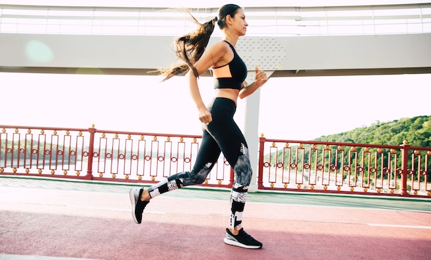 Close up shot of jogging beautiful brunette sporty woman in cool wear