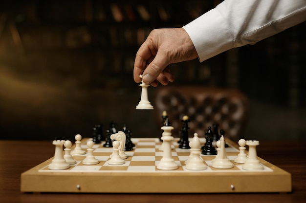 チェス盤上でチェスの駒を動かす男性の手のショットを閉じる