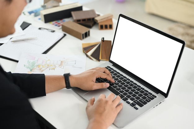 Close up shot of male interior designer using laptop at creative workplace