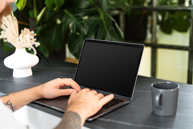 Immagine ravvicinata di un uomo seduto al tavolo e che lavora al computer portatile a casa