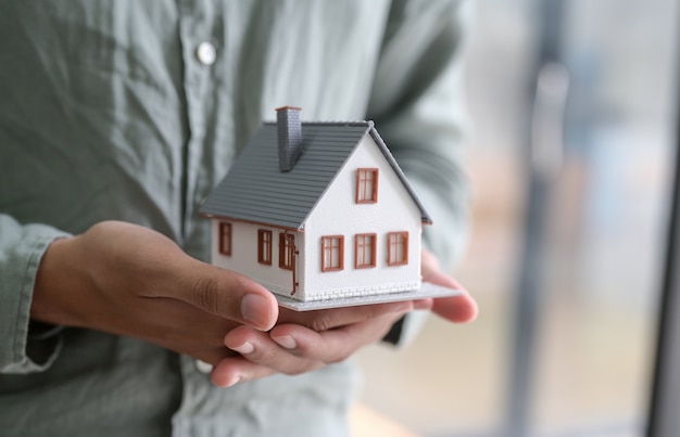 Close up shot of person holding model house in hand