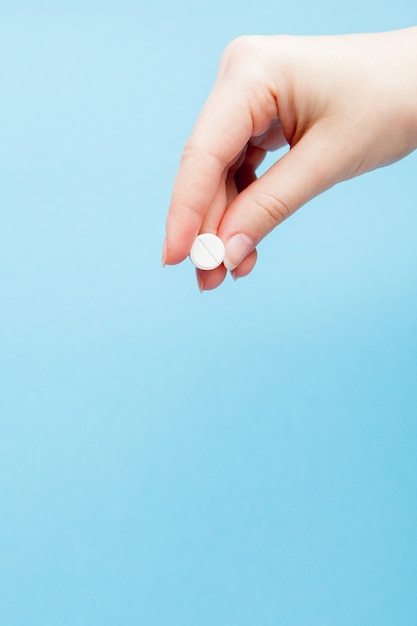 Close-up shot of pill in nurse's hand isolated over blue background. Copy space.