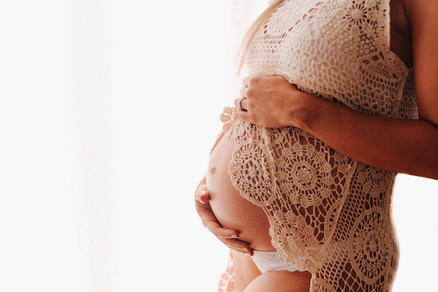 Close up shot of a pregnant belly on a white background while touching her belly. Copy space