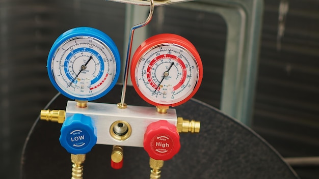 Close up shot of pressure measurement device used for checking condenser freon pressure. Set of manifold indicators showing high or low refrigerant levels in outdoor air conditioner