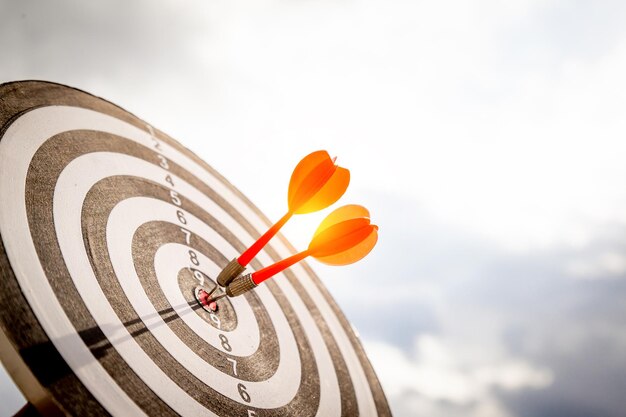 Close up shot red darts arrows in the target of dartboard
center on dark blue sky background business target or goal success
and winner concept