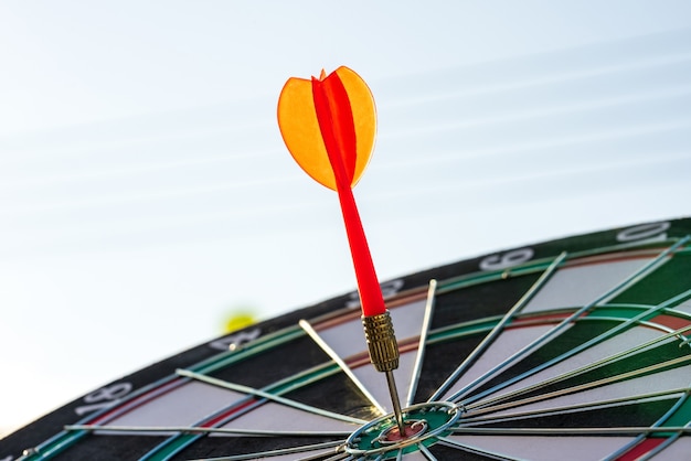 Close-up shot rode dartpijl die in het doelcentrum van het dartbord raakt, bedrijfsdoel of doelsuccesconcept.