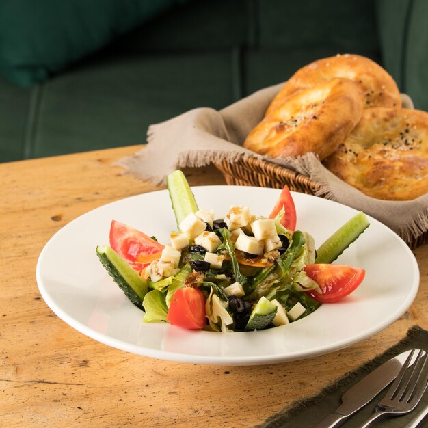 Close up shot of a salad and appetizers near basket of breads