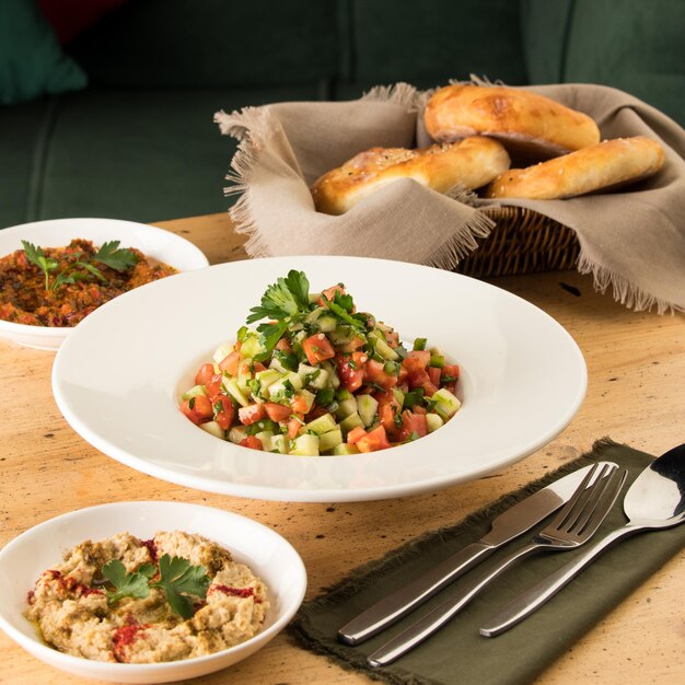 Close up shot of salads and appetizers near basket of breads