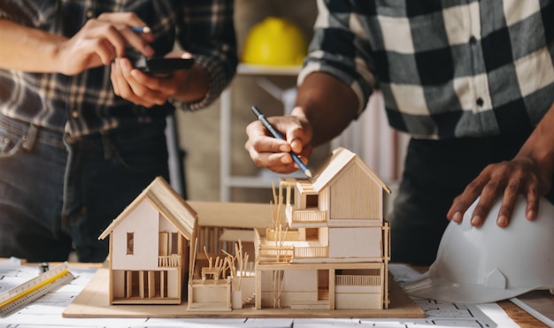 Photo close up shot of scale model house on table with architects two architects making architectural model in office together to form a new buildingxa