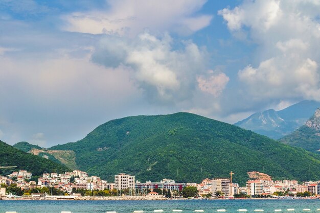 Primo piano del mare e del paesaggio urbano ai piedi delle montagne sulla riva in una giornata luminosa. l'antica città di mare di budva in montenegro sulla costa del mare adriatico