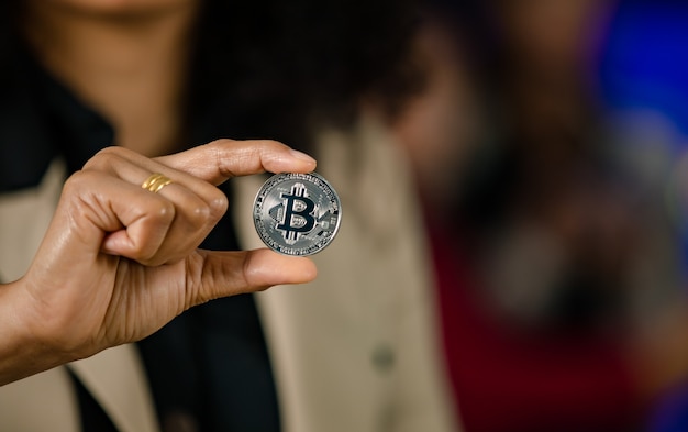 Photo close up shot of silver bitcoin cryptocurrency virtual token coin in professional successful female businesswoman trader investor hand with copy space in blurred background.