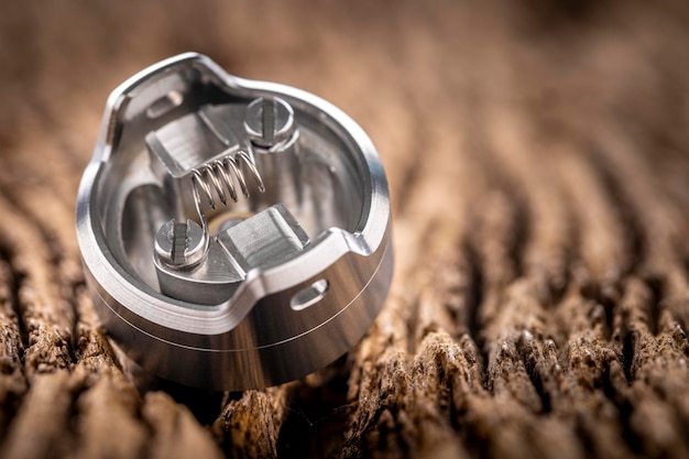 Close up shot of single space coil in high end rebuildable dripping atomizer for flavour chaser on rustic natural wood texture background vaping device