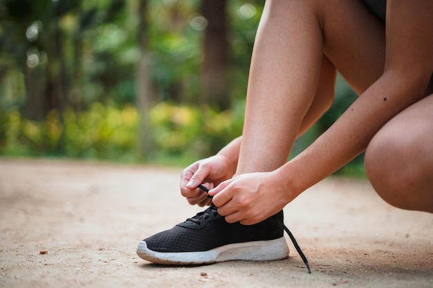 Immagine ravvicinata di donna sportiva che lega i lacci delle scarpe nel parco