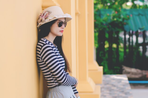 Chiuda sul colpo della giovane donna alla moda in occhiali da sole e cappello.