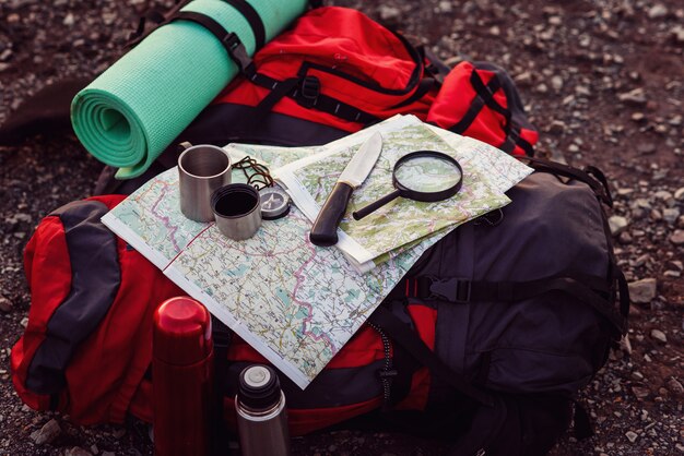 Close up shot of travel equipment, backpack, map, compass, knife, sleeping pad on the ground