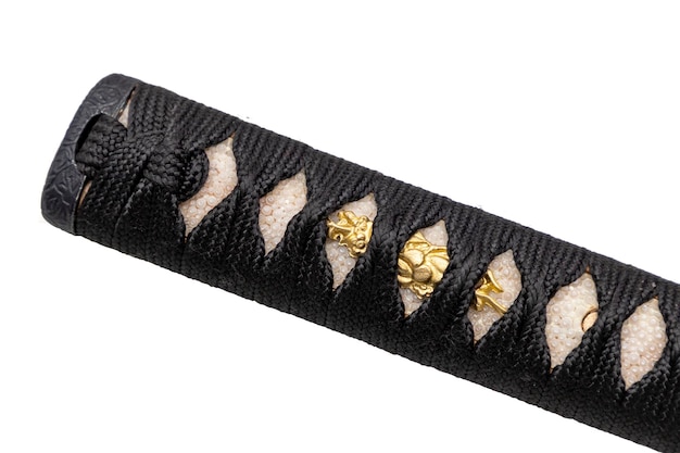 Close up shot of Tsuka handle of Japanese sword wrapped by black silk cord on white ray skin with a small piece of gold decoration called Menuki isolated in white background Selective focus