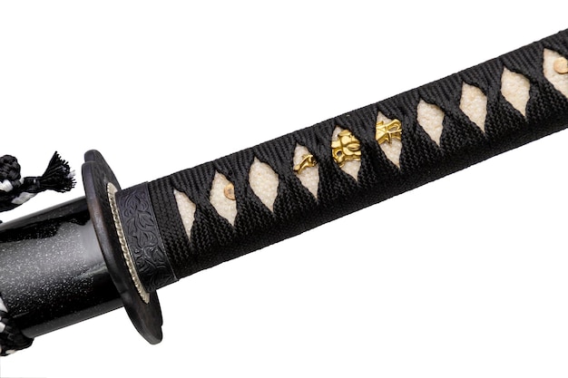 Крупный план рукояти японского меча Цука, обернутой черным шелковым шнуром на коже белого луча, с небольшим золотым украшением под названием Менуки, изолированным на белом фоне Выборочный фокус