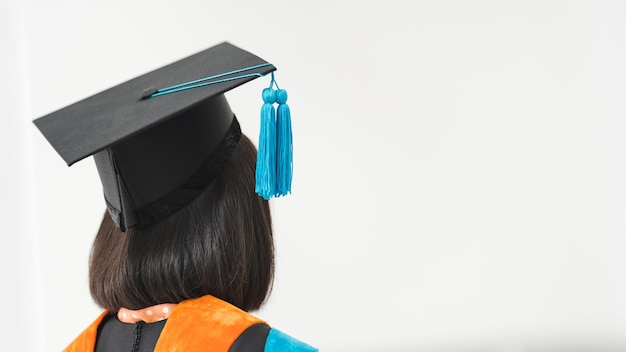 Close-up shot of a university graduate in graduation gown holding a degree certification with mortarboard to shows and celebrates success in the college commencement day. Education stock photo