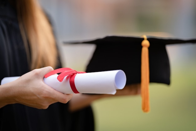 Photo close-up shot of a university graduate holding a degree certification to shows and celebrate education success on the college commencement day. education stock photo