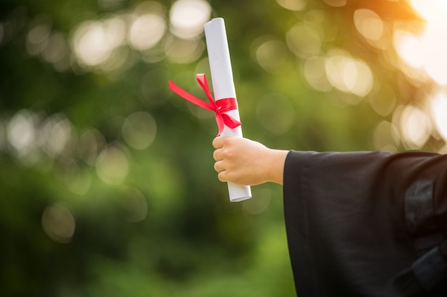 Foto primo piano di un laureato in possesso di una certificazione di laurea per mostrare e celebrare il successo dell'istruzione all'università