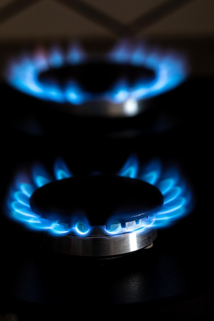 Close-up shot van blauw vuur van binnenlandse keuken kookplaat Brandende gasfornuisbrander Gasfornuis met brandende vlammen van propaangas Industriële hulpbronnen en economieconcept