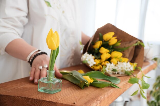 close-up shot van bloemist die een boeket van gele tulpen maakt in bloemenwinkel