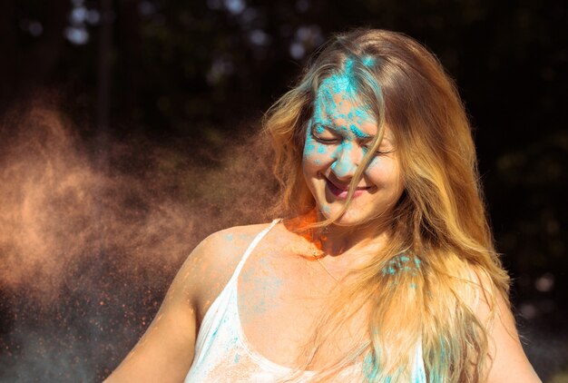 Close-up shot van coole blonde vrouw met lang krullend haar die Holi-festival viert