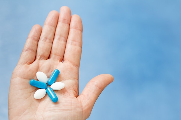 Close-up shot van de hand met blauwe en witte pillen in de vorm als bloem. Pillen aan de kant van de vrouw