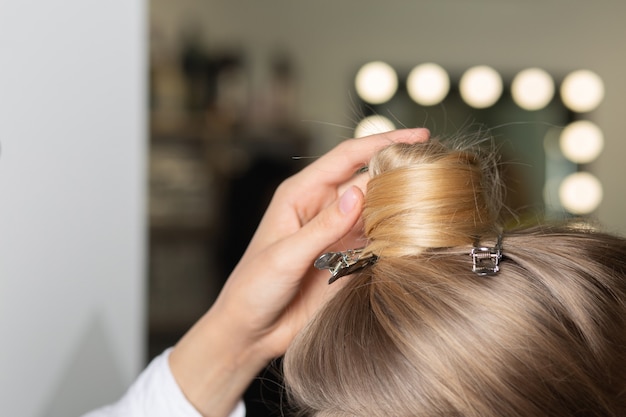 Close-up shot van de hand van de kapper die haar voorbereidt op styling in een schoonheidssalon