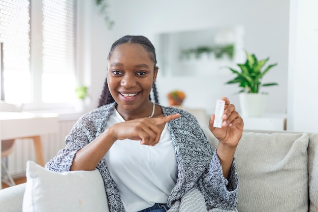 Close-up shot van de hand van een Afro-Amerikaanse vrouw die een negatief testapparaat vasthoudt. Gelukkige jonge vrouw die haar negatieve Coronavirus laat zien - Covid-19 snelle test. Focus ligt op de test.Coronavirus