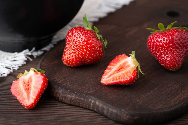 close-up shot van een aardbei in tweeën gesneden op een donkere snijplank