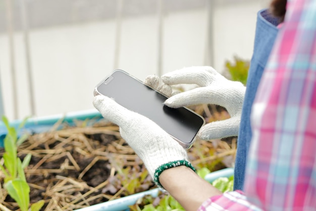 Close-up shot van een Aziatische boerin met behulp van een smartphone