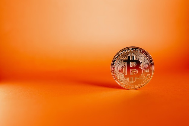 Close-up shot van een Bitcoin geïsoleerd op een oranje achtergrond met kleurovergang